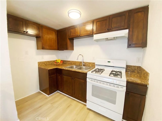 kitchen featuring light hardwood / wood-style flooring, sink, dark stone counters, and gas range gas stove