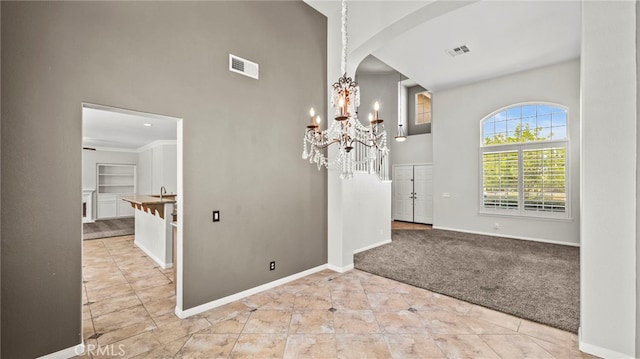 interior space with a chandelier, crown molding, built in features, sink, and light carpet