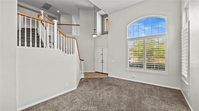 carpeted entryway featuring a high ceiling