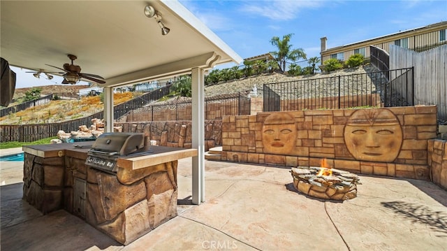 view of patio / terrace with area for grilling, ceiling fan, an outdoor fire pit, and an outdoor kitchen