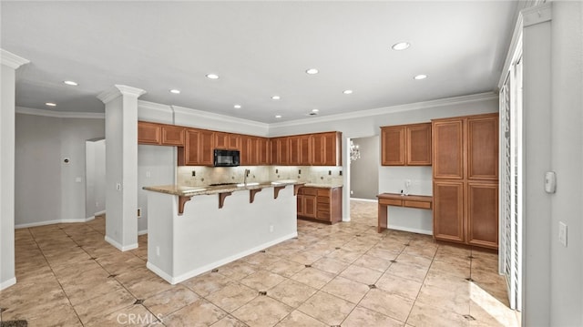 kitchen with light stone counters, ornamental molding, tasteful backsplash, a kitchen island, and a kitchen bar