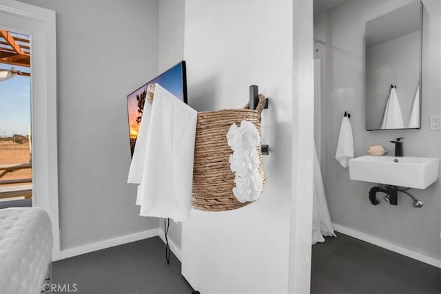 interior space with concrete floors, a sink, and baseboards