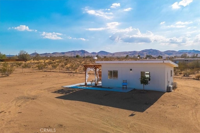 exterior space featuring view of desert, a mountain view, and a patio area