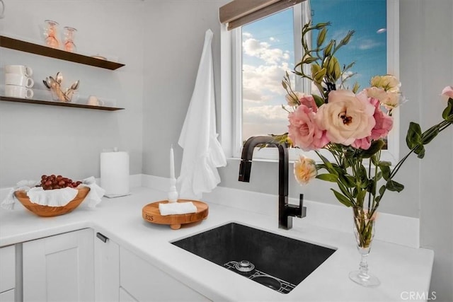 room details with white cabinetry, open shelves, light countertops, and a sink