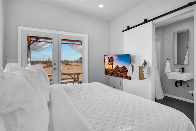 bedroom featuring recessed lighting, a barn door, access to exterior, a sink, and baseboards