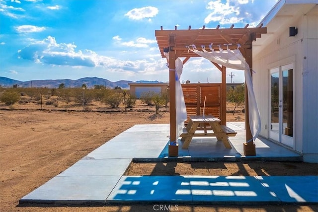 view of patio / terrace with a pergola, french doors, and a mountain view