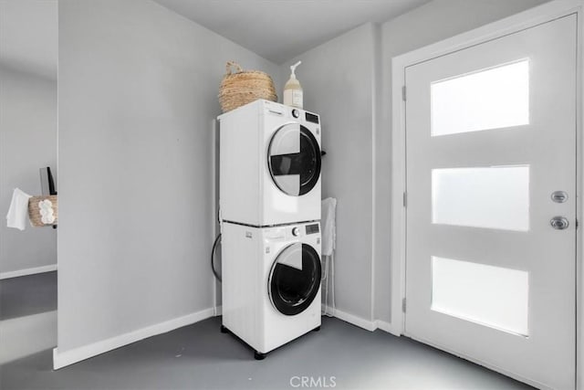 laundry room featuring stacked washer / drying machine, laundry area, and baseboards