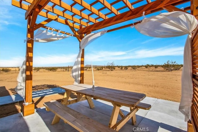 view of patio featuring outdoor dining space, a rural view, and a pergola