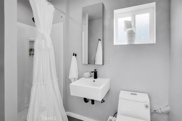 bathroom featuring toilet, a shower with curtain, and sink