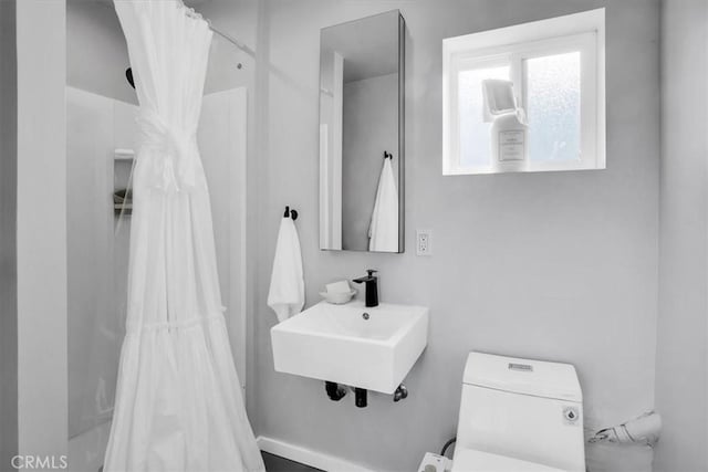bathroom with toilet, a shower with shower curtain, and a sink