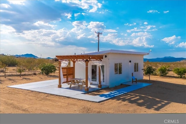 back of property featuring a mountain view, a pergola, and a patio area