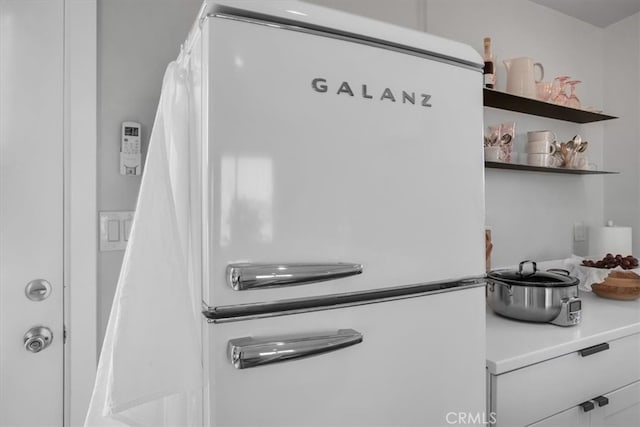 details featuring white cabinets and white fridge