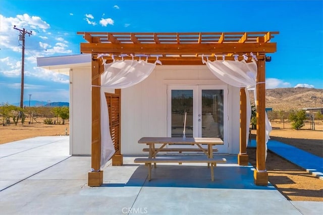view of patio with french doors, a pergola, and a mountain view