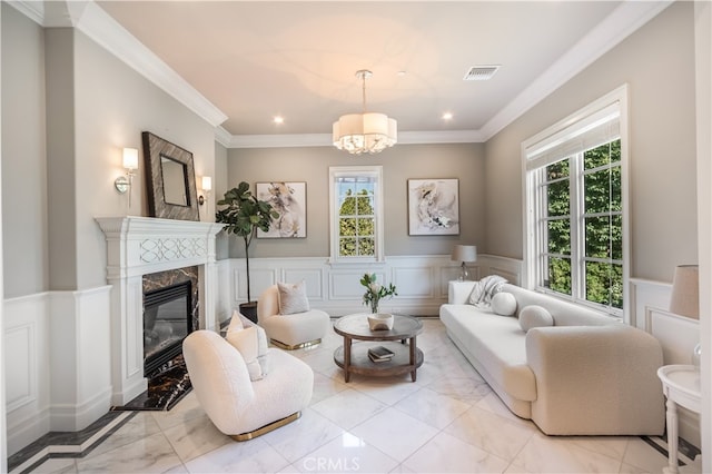 living room featuring a notable chandelier, a high end fireplace, a healthy amount of sunlight, and crown molding