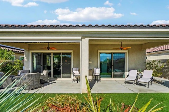 back of house featuring a lawn, ceiling fan, and a patio area