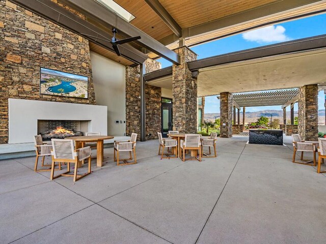 view of patio featuring a mountain view and an outdoor stone fireplace