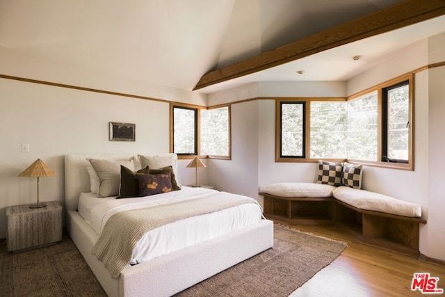 bedroom featuring wood-type flooring and vaulted ceiling with beams