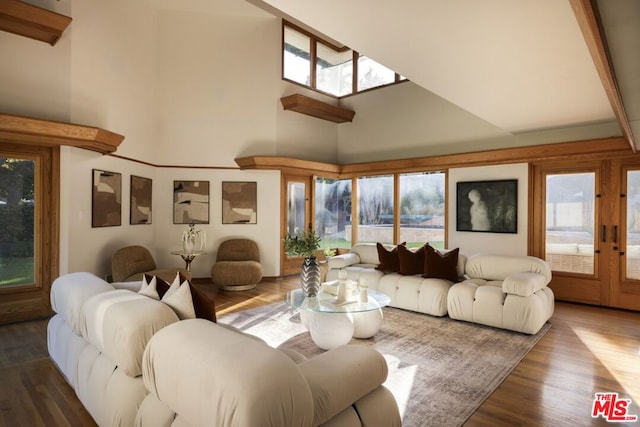 living room with a healthy amount of sunlight, beam ceiling, a towering ceiling, and wood-type flooring