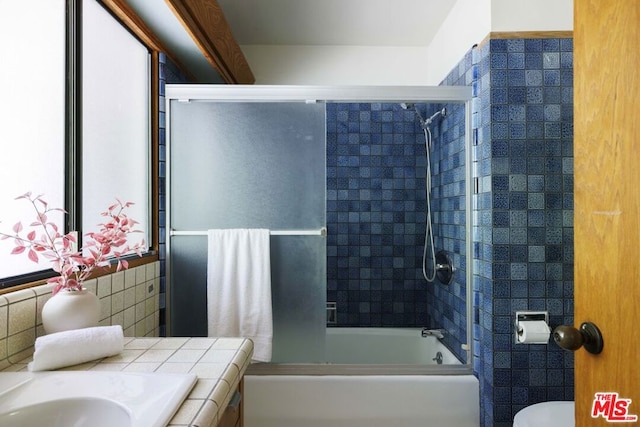 bathroom with shower / bath combination with glass door and toilet