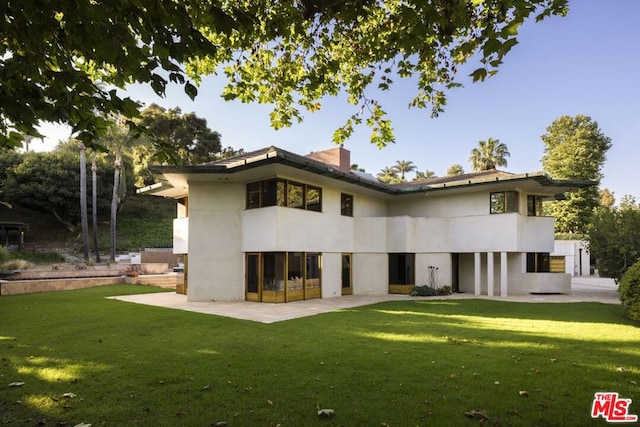 back of property with a lawn and a patio area