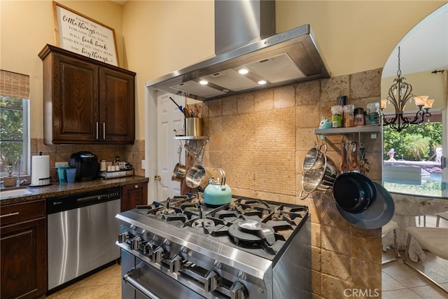 kitchen with light tile patterned flooring, dark brown cabinets, extractor fan, appliances with stainless steel finishes, and an inviting chandelier