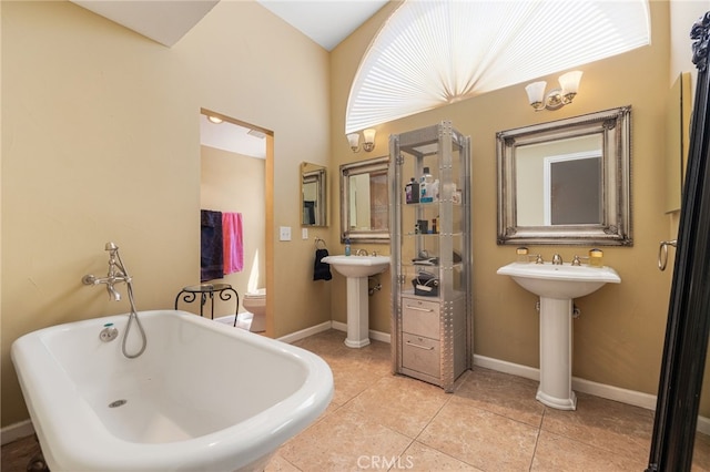 bathroom featuring sink, toilet, a bath, and tile patterned floors