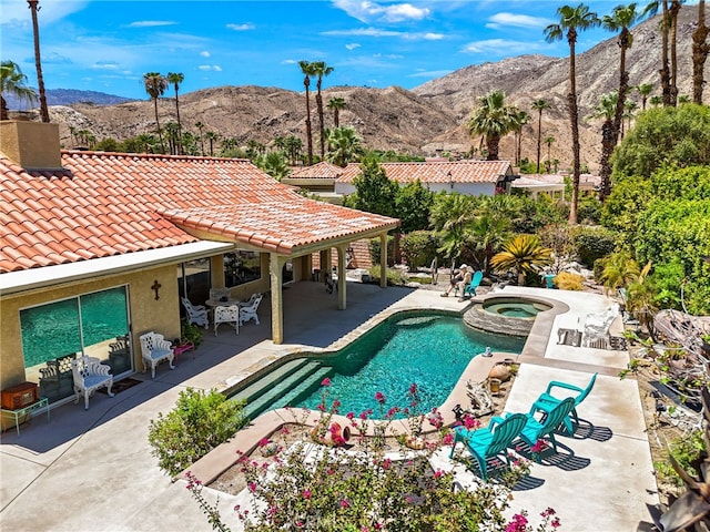 view of swimming pool with a mountain view, an in ground hot tub, and a patio area