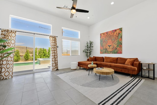 living room with ceiling fan, light tile patterned flooring, and a towering ceiling