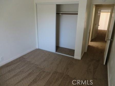 unfurnished bedroom featuring dark colored carpet and a closet