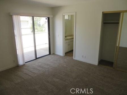 unfurnished bedroom with access to outside, ensuite bath, a closet, and dark colored carpet