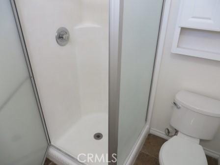 bathroom featuring tile patterned floors, toilet, and a shower with shower door