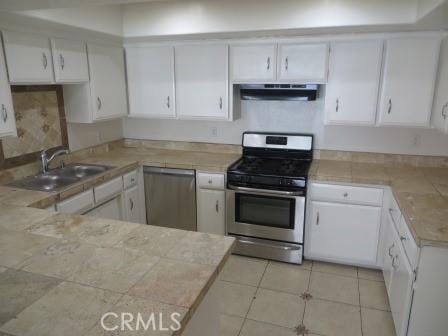 kitchen with sink, white cabinets, stainless steel appliances, and range hood