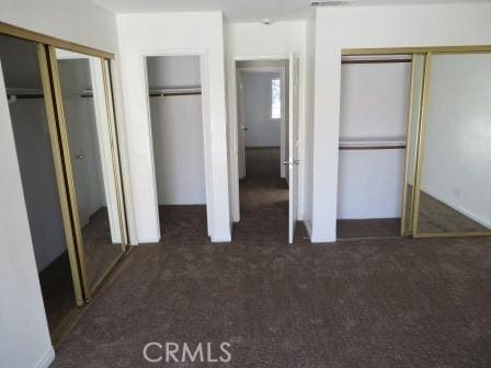 unfurnished bedroom with two closets and dark colored carpet