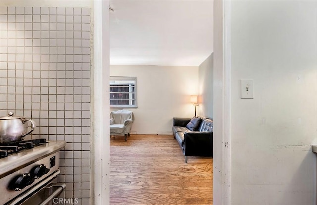 interior space featuring stainless steel range, light hardwood / wood-style floors, and tile walls