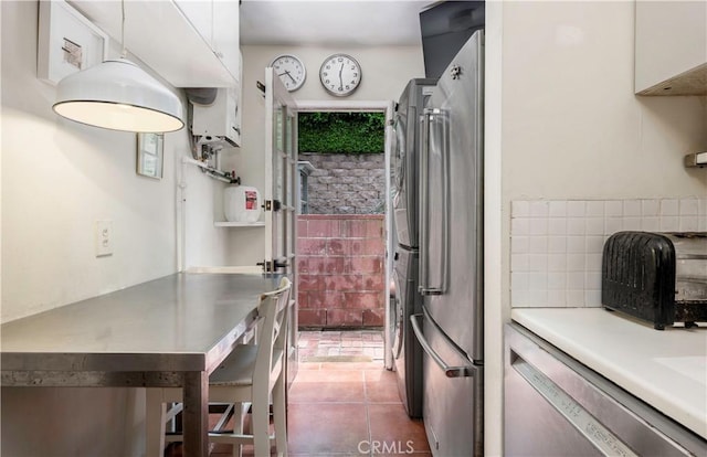 kitchen with stainless steel fridge, dark tile patterned floors, and white cabinetry