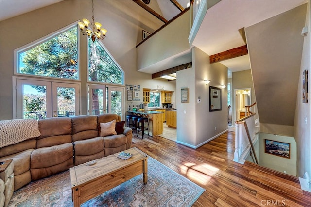 living room featuring high vaulted ceiling, light hardwood / wood-style flooring, beam ceiling, and a notable chandelier