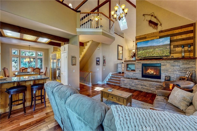 living room with a towering ceiling, hardwood / wood-style floors, a chandelier, and a fireplace