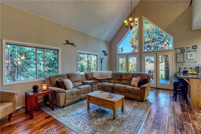 living room with high vaulted ceiling, a wealth of natural light, dark hardwood / wood-style flooring, and a chandelier