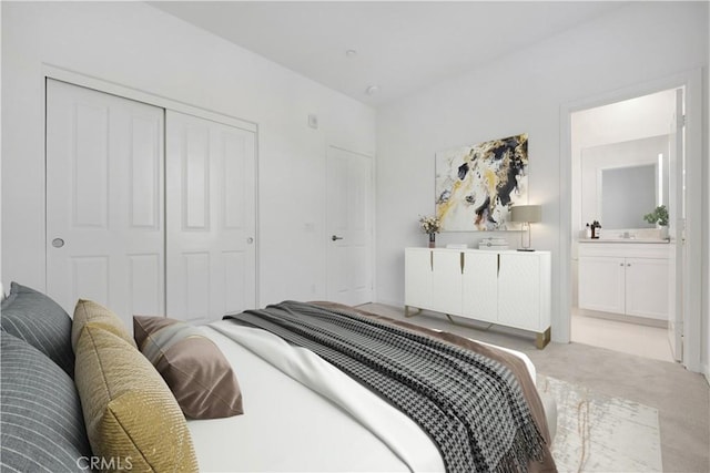 bedroom with ensuite bathroom, light colored carpet, and a closet