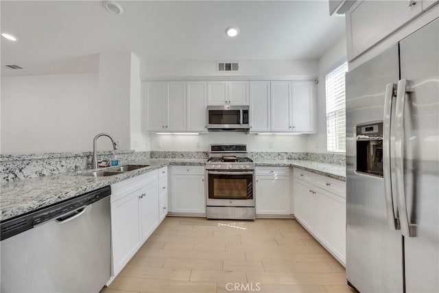 kitchen featuring white cabinetry, sink, light stone counters, and appliances with stainless steel finishes