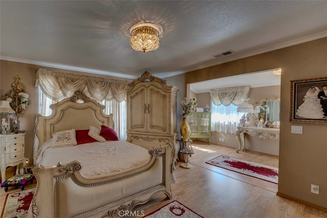 bedroom featuring a textured ceiling, light hardwood / wood-style floors, and ornamental molding