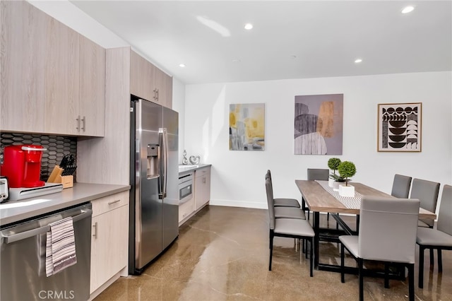 kitchen featuring light brown cabinetry, stainless steel appliances, and tasteful backsplash