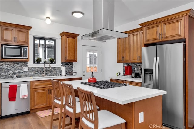 kitchen with tasteful backsplash, sink, a kitchen island, island range hood, and stainless steel appliances