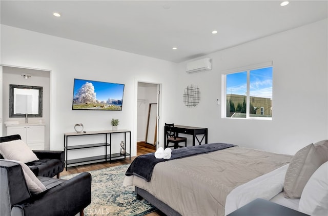 bedroom featuring sink, a wall unit AC, ensuite bathroom, and wood-type flooring