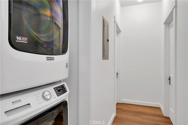 laundry area featuring stacked washing maching and dryer, electric panel, and light wood-type flooring