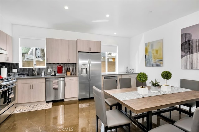 kitchen featuring decorative backsplash, stainless steel appliances, light brown cabinetry, and sink