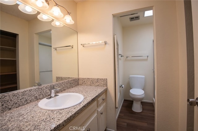 bathroom featuring vanity, wood-type flooring, and toilet