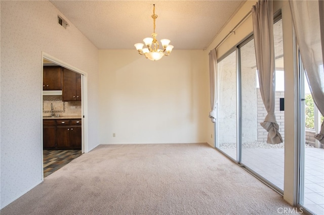 unfurnished room with an inviting chandelier, a textured ceiling, sink, and carpet