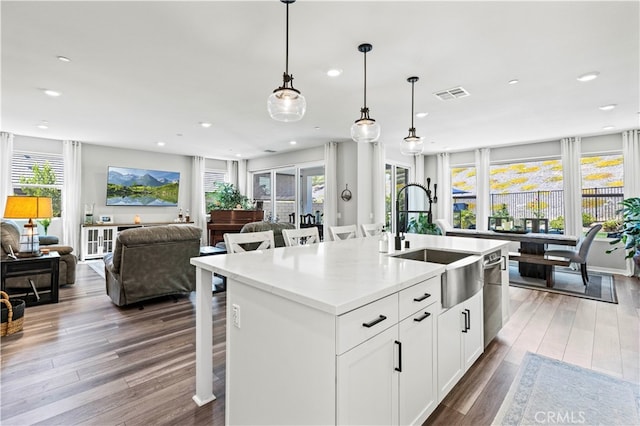 kitchen featuring a wealth of natural light, hardwood / wood-style flooring, a kitchen island with sink, and white cabinetry