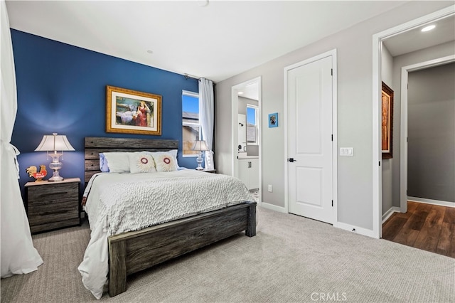 bedroom with ensuite bath and hardwood / wood-style floors